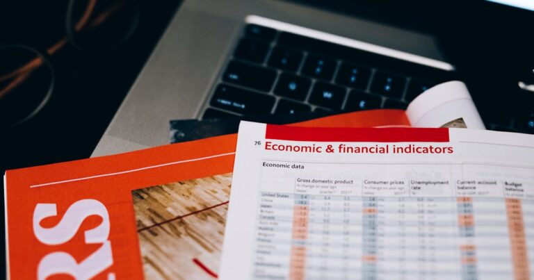 Detailed close-up of economic and financial documents on a laptop keyboard, highlighting data analytics.