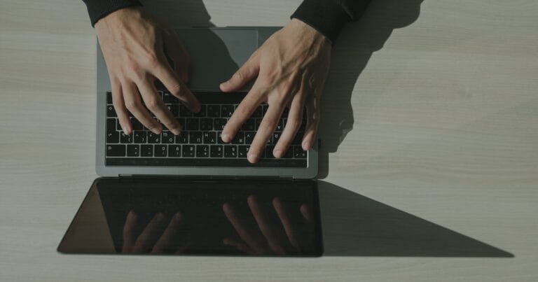 Overhead shot of hands typing on a laptop, showcasing technology and internet usage.